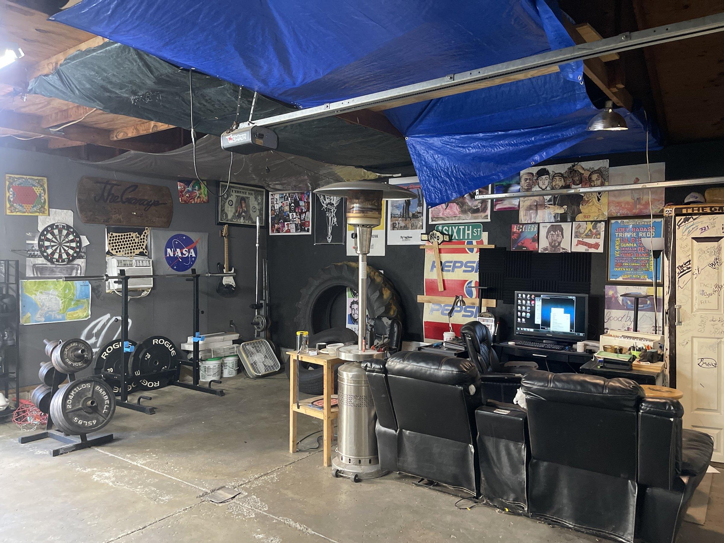 The Square1 garage with blue tarps on the ceiling, posters on the walls, recliners, and a desk with a monitor